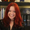 Woman with red hair in front of a bookcase