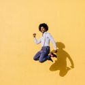 Freeze frame of A man and his shadow jumping against a yellow background