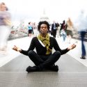 Picture of a man meditating in the center of a busy sidewalk