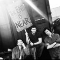 Supernatural actors, Jared Padalecki, Jensen Ackles, and Misha Collins holding a sign that says "The End is Near"