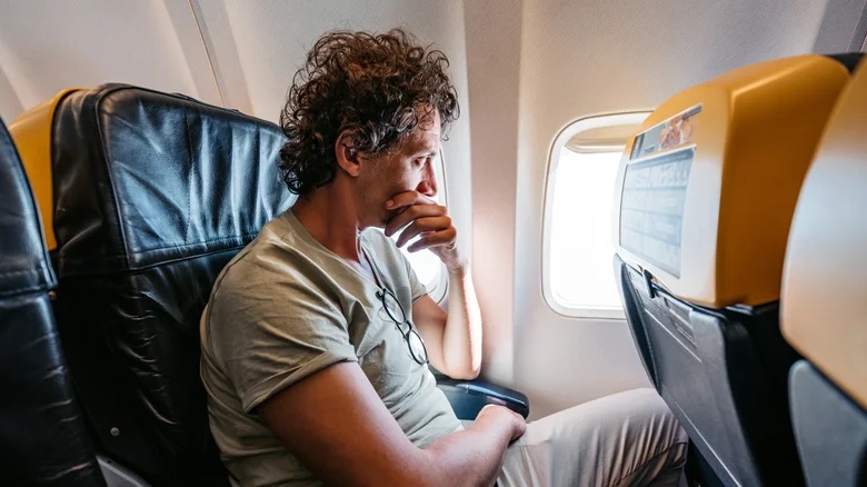 Man staring nervously out of an airplane window. 